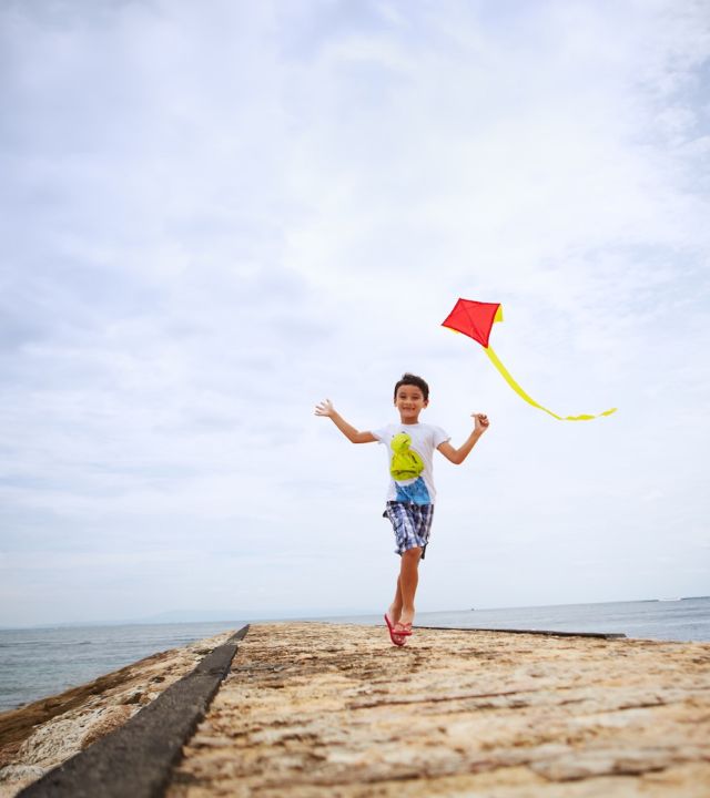 Kid Running Along with Kite near Ocean