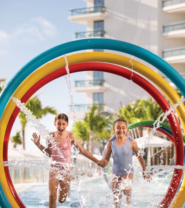 Two girls holding hands and running through a waterpark