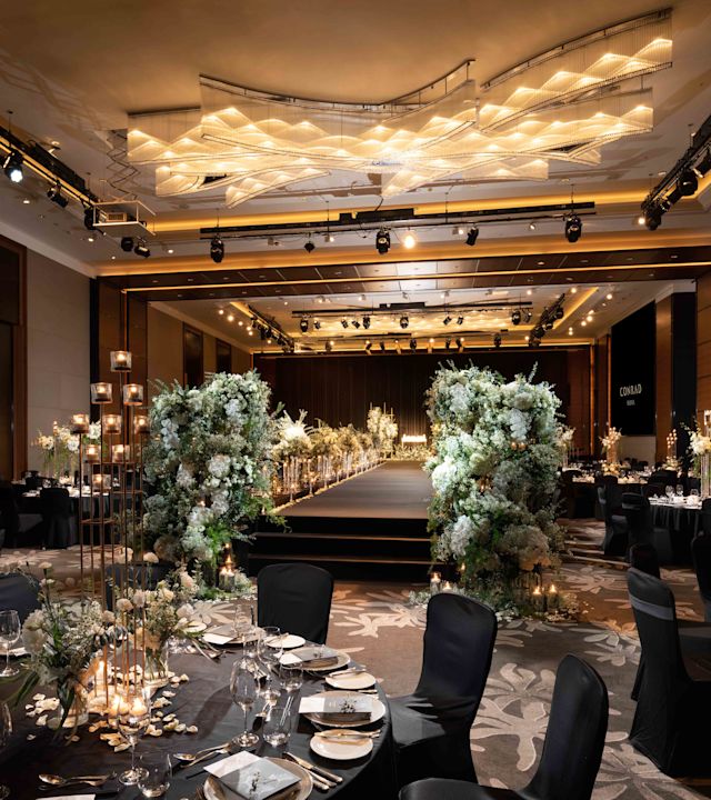 Grand Ballroom decorating for a stunning Wedding. A walkway is surrounded by flowers and elegant tables.