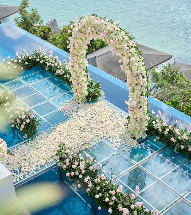 Arc de flori într-o zonă orientată spre apă pentru a sărbători o nuntă