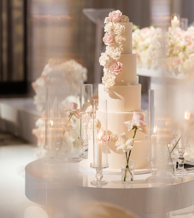 横にピンクのバラが散りばめられた3段ウェディングケーキ