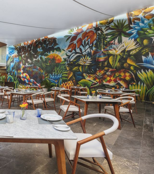 Seating area with tables and chairs with a large mural on wall