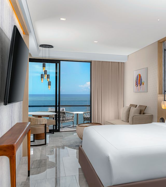 Habitación de lujo frente al mar con dormitorio con cama King, TV montado en la pared y sofá