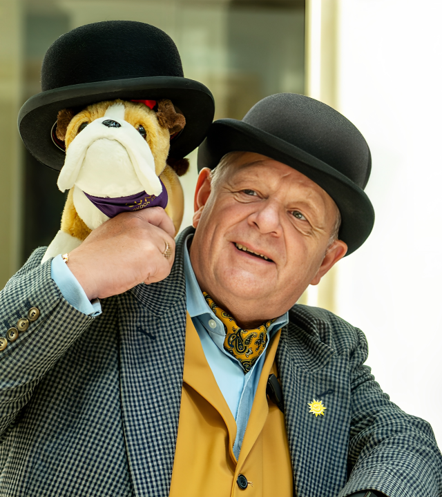 Concierge Holding a Stuffed Dog Wearing a Hat