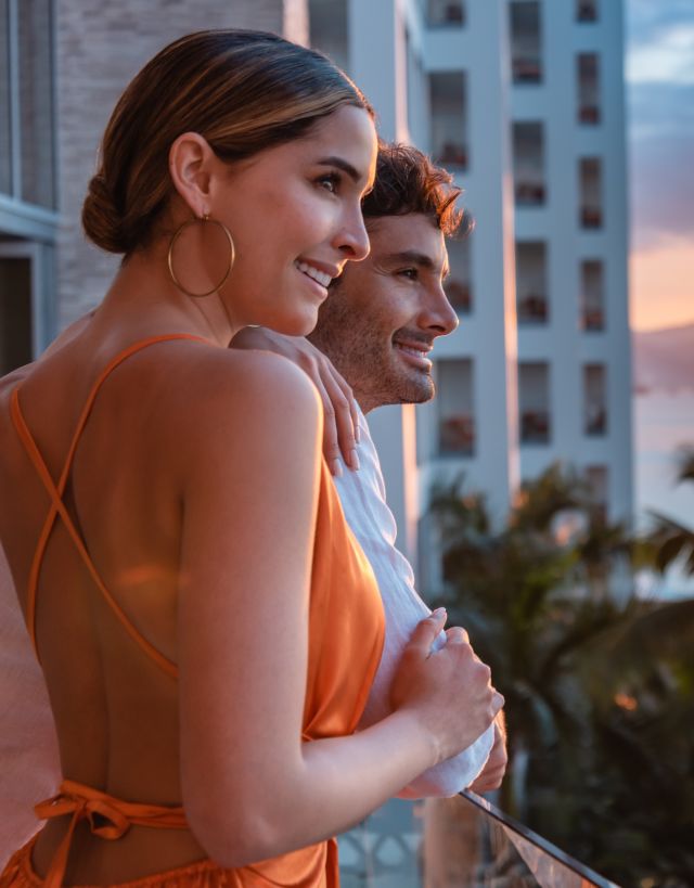A couple enjoying the view from their guest room balcony at unset