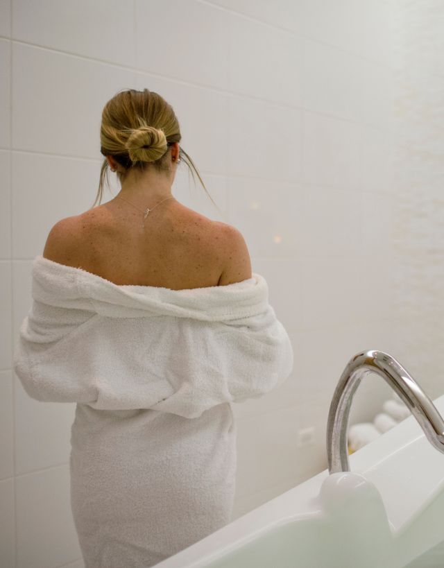 Woman in robe standing near bath