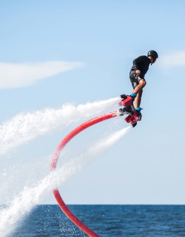 Person using a water jetpack to fly above ocean
