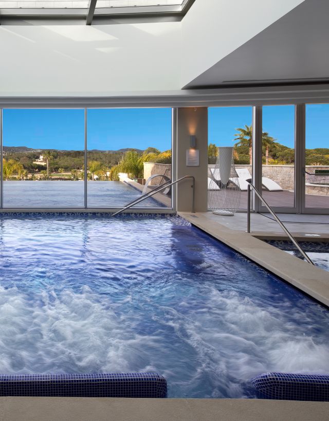 Indoor whirlpool looking out to an outdoor infinity pool