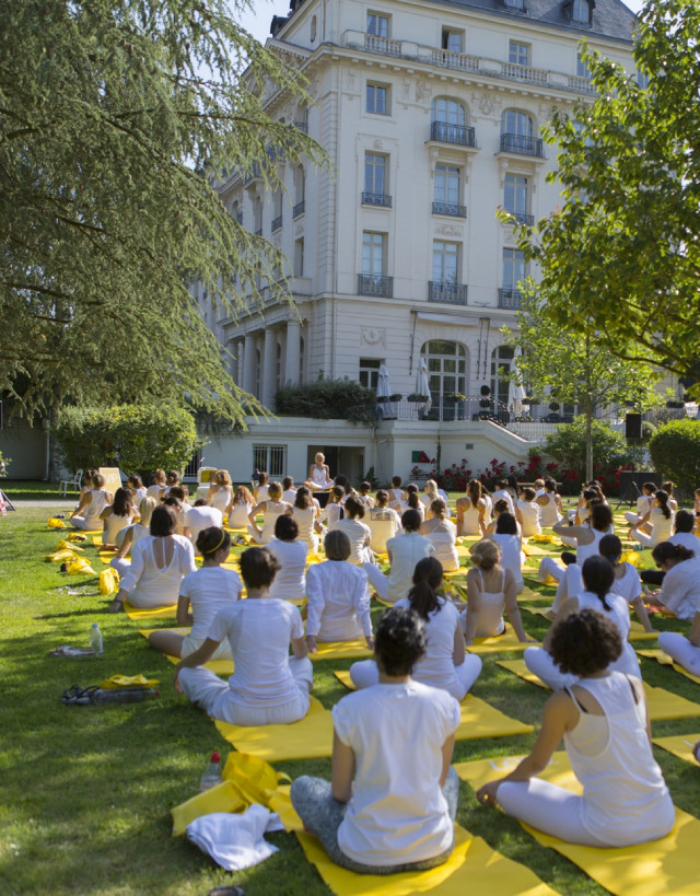 a group of people practicing yoga on lawn of the hotel