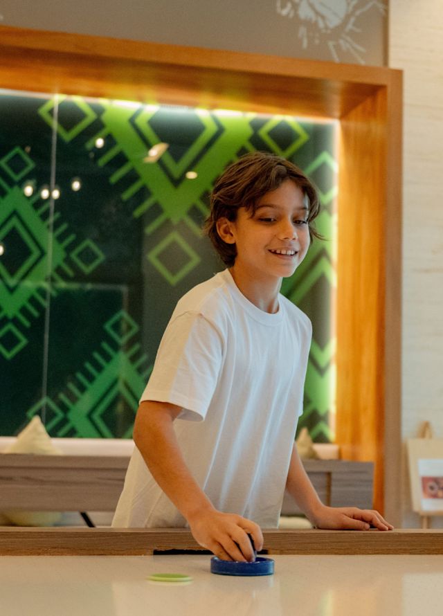 Băiat care joacă hochei pe calea aerului la clubul pentru copii