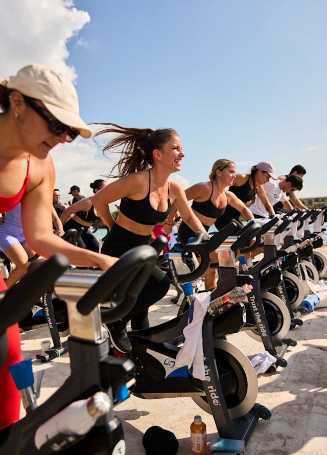 Oameni care fac fitness în exterior cu aparate de cardio