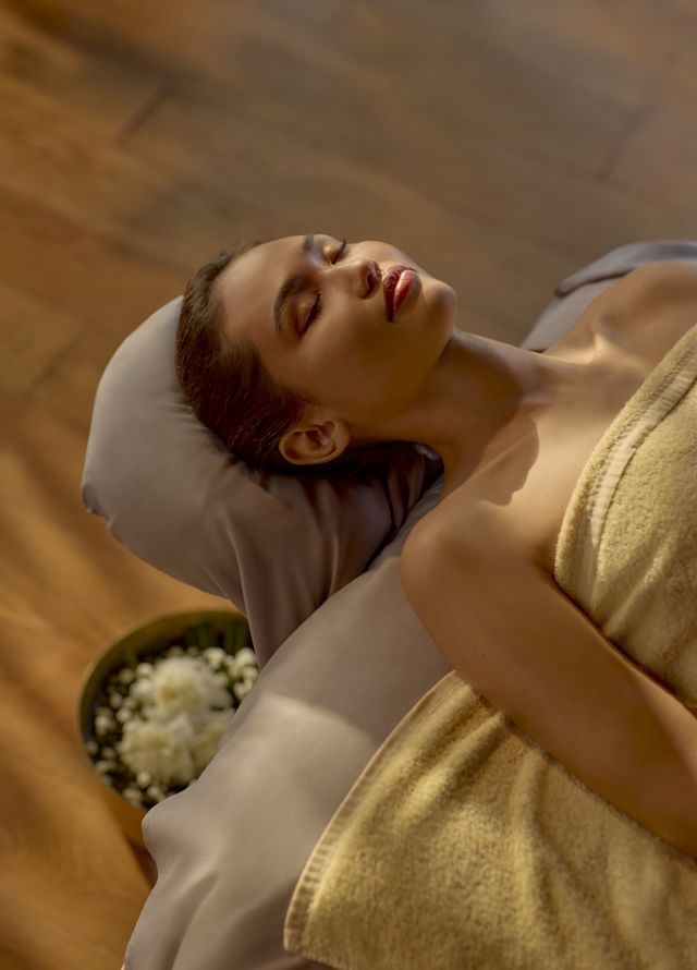 Woman in towel relaxing on spa treatment table