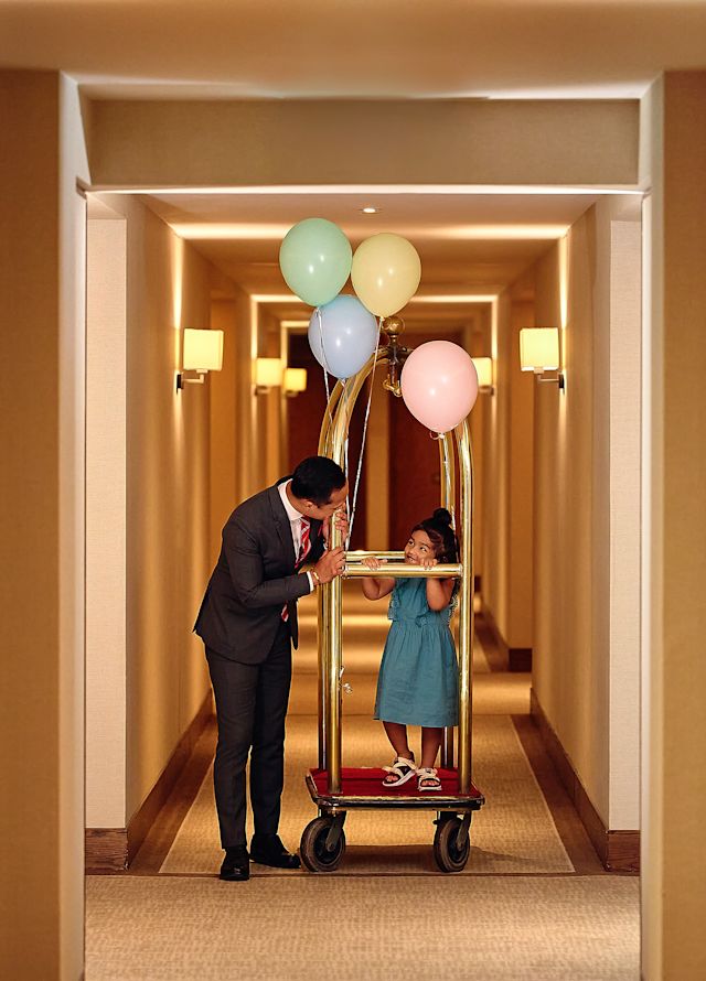 Tată și fiică pe căruciorul de bagaje de pe hol