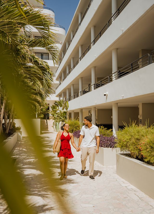 Couple Holding Hands is Walking on Hotel Grounds