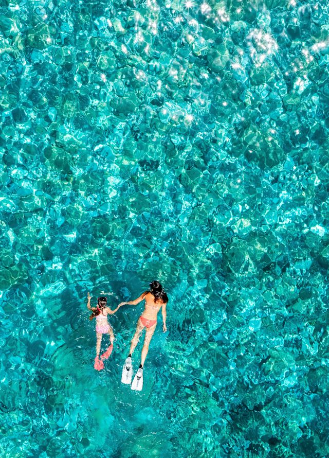Vista aérea aérea de uma mãe e filha mergulhando com snorkel