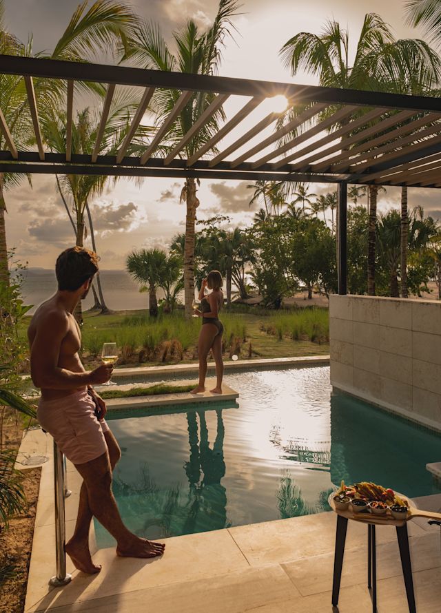 Man and woman having drinks and standing around the suite's plunge pool,