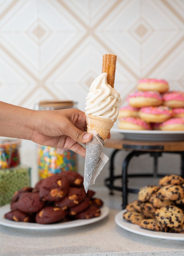 Una persona sosteniendo un cono de helado en el restaurante La Churrería