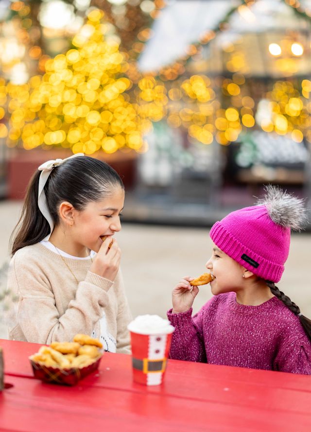 Girls Enjoying Cookies and Hot Chocolate Outdoors at Christmas Time