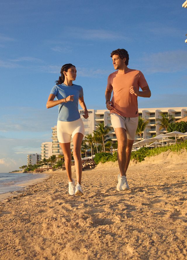 Uomo e donna che fanno jogging sulla spiaggia dell'hotel