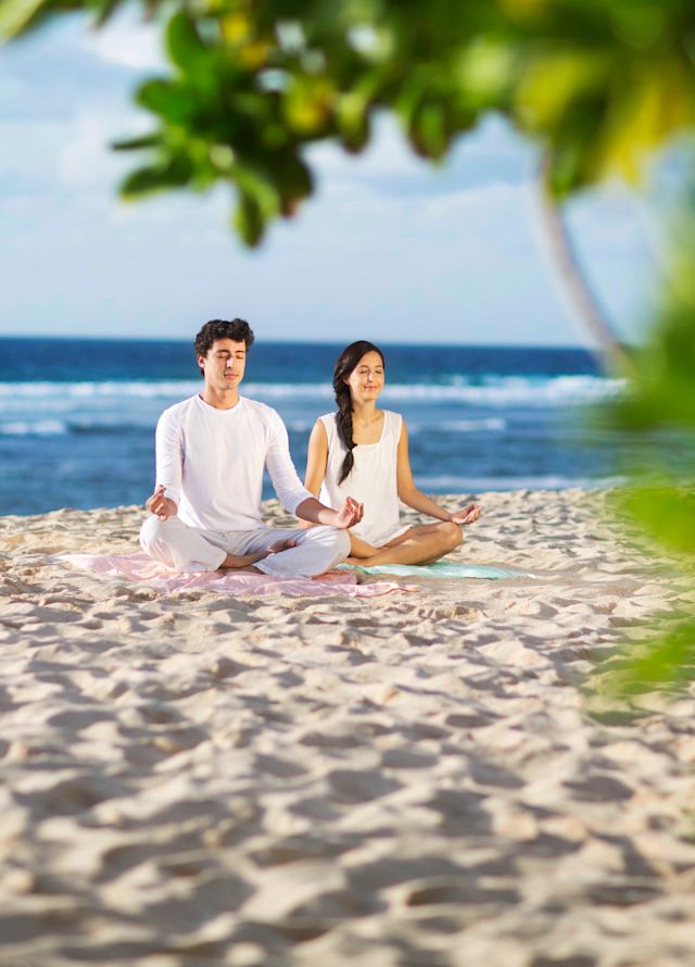 Paar am Strand meditiert in Lotusposition