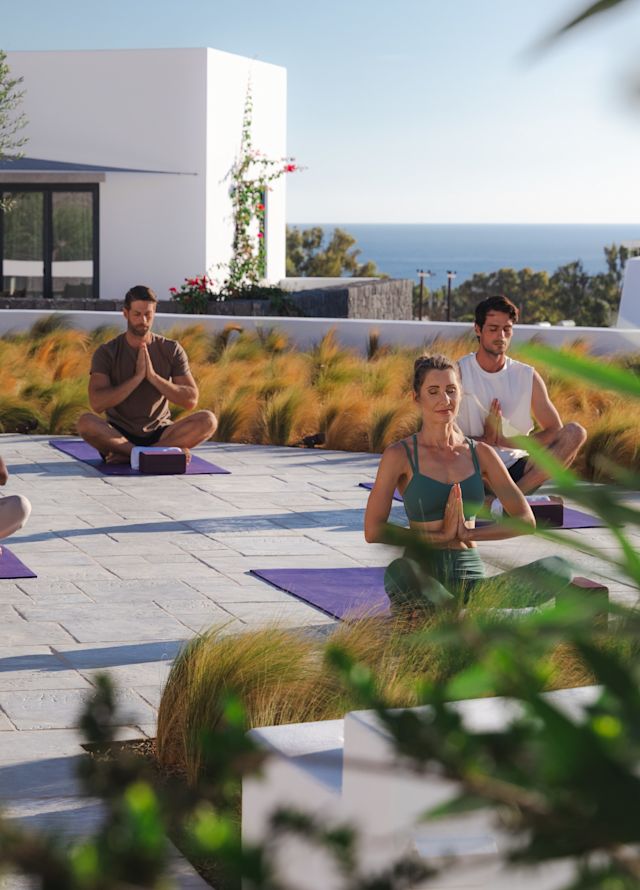 Deniz manzaralı açık alanda yoga yapan bir grup insan