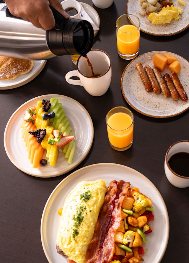 Waiter serving coffee in a table setup with breakfast foods