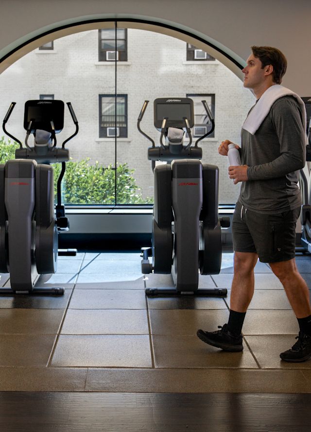 A man in a fitness center with elliptical machines and other exercise equipment