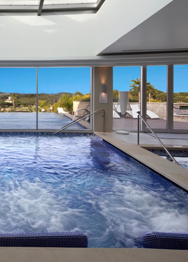 Indoor whirlpool looking out to an outdoor infinity pool
