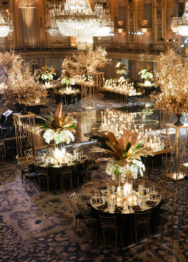 Chandeliere mari într-o sală de bal decorată cu flori și lumânări pentru a sărbători o nuntă