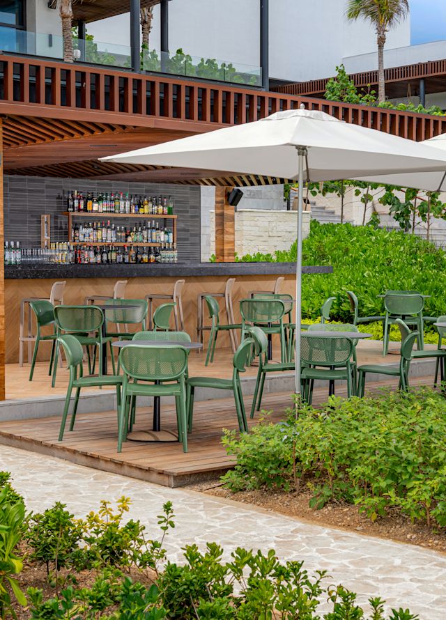 Pool Bar with Dining Area Outdoors under Umbrellas by a Garden with Palm Trees