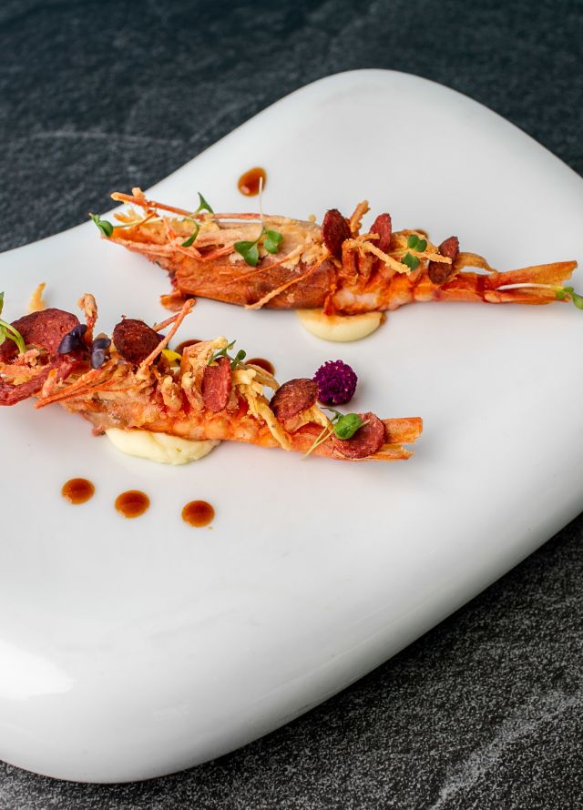 Two langoustines on a white curved slab