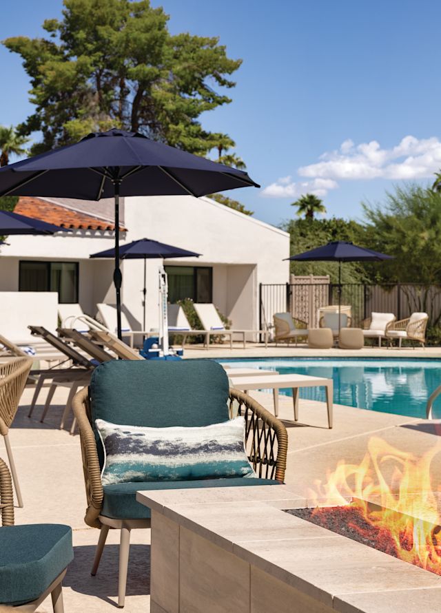 Outdoor patio with gas fireplace, soft seating, and a pool.
