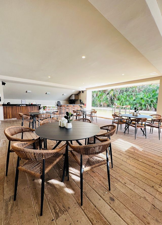 Penyiapan tablet restoran dengan kursi rotan dan area pohon luar ruangan