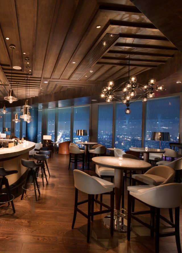 Sip Wine bar with high-top tables, chairs, and windows with outdoor view, lit up at night