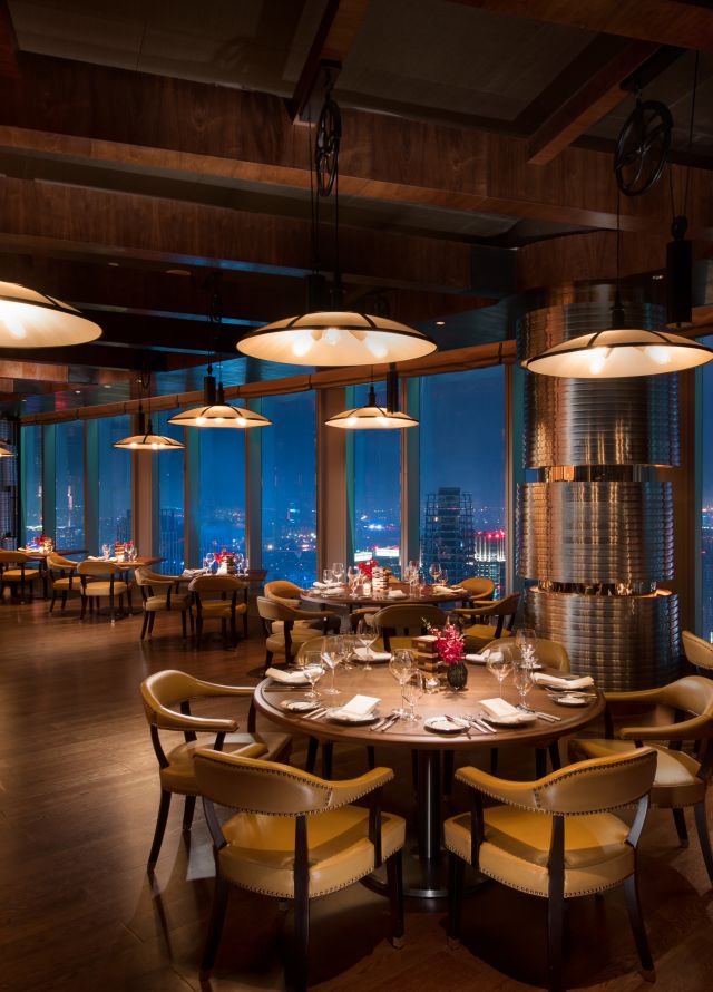 Limited Edition Grill restaurant with dining tables, chairs, dining amenities, and floor-to-ceiling windows with city view at night