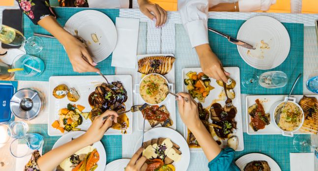 Top down shot of food on blue table with peoples hands