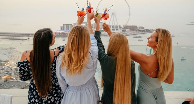 Group of women toasting their drinks with the Dubai Eye in the background