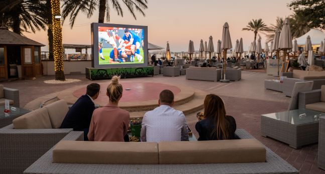 People watching sports on a big screen outside at Wavebreaker