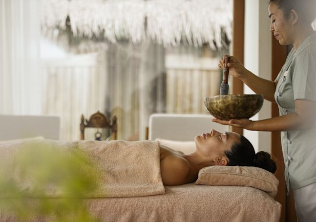 スパで癒しの音を聞きながらリラックスする女性