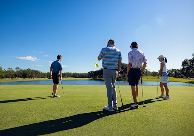 Personer som spelar golf på Cypress Course med en vattenfunktion