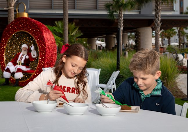 Kids decorating Santa cookies outdoors