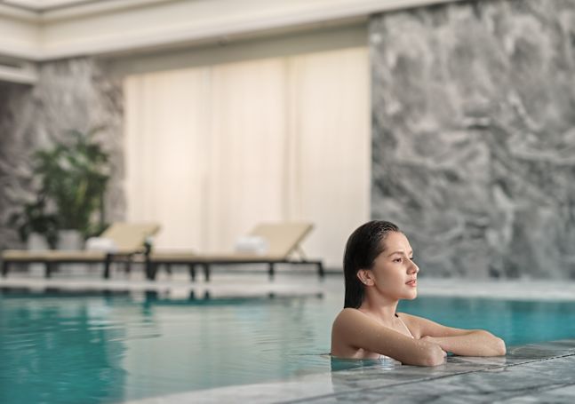Woman relaxing by edge of indoor pool