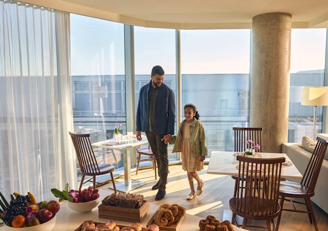 Mann geht Hand in Hand mit jungem Mädchen zum Tisch mit Gebäck und Obst