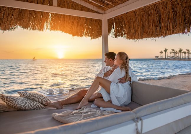 Casal em uma cabana na praia olhando para o pôr do sol