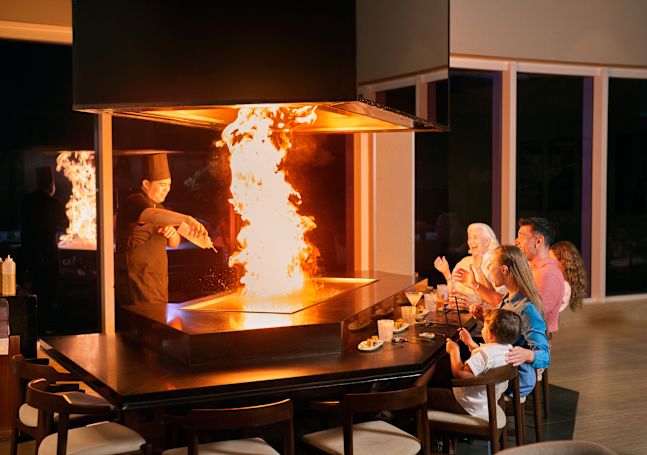 Family Enjoying Watching a Chef Cooking with Fire on a Grill at Noriku Restaurant