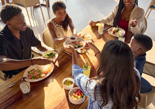 Мать, отец, дочь, сын и подруга семьи или член семьи вместе обедают в Cocomar