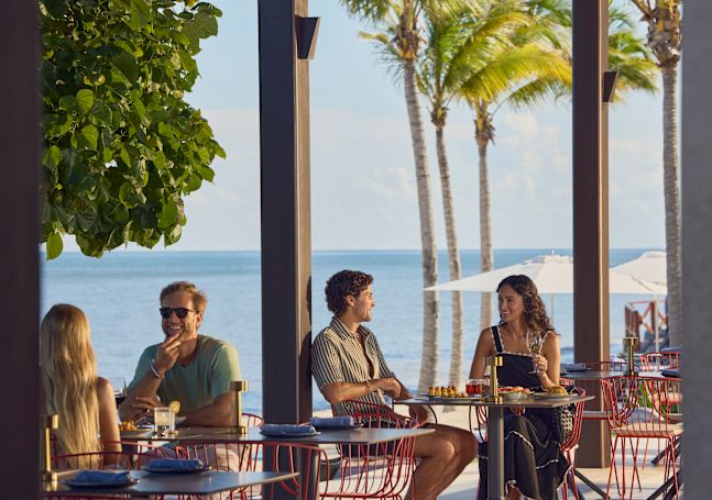 Two couples on separate tables enjoying a meal at the beachside restaurant