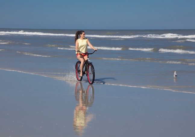 Frau beim Radfahren am Strand am Tag