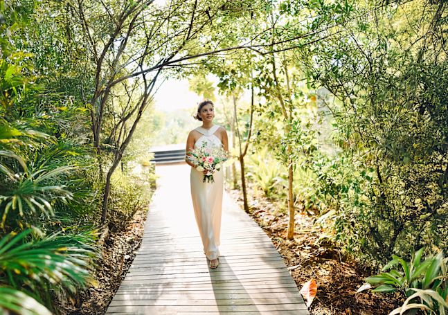 Bride walking down a path holding bouquet of flowers
