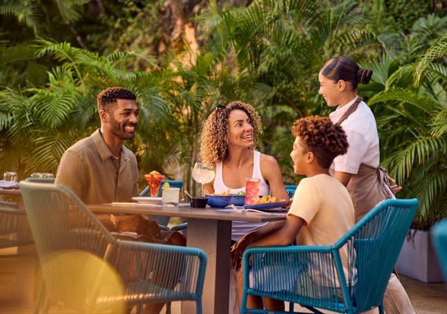 Père, mère et fils savourant un repas sur la terrasse du restaurant